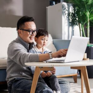 Father holding son working on laptop